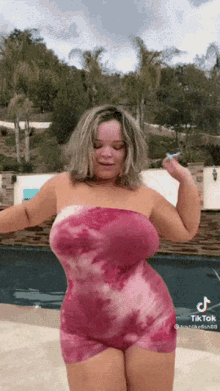 a woman in a pink dress is dancing in front of a pool .